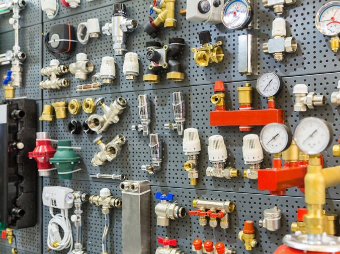 brass and steel plumbing valves and fixtures on the wall in a plumning supply wholesaler