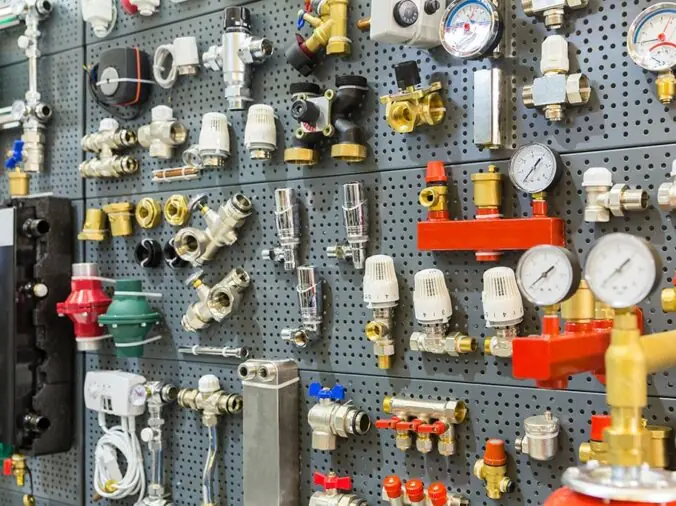 brass and steel plumbing valves and fixtures on the wall in a plumning supply wholesaler